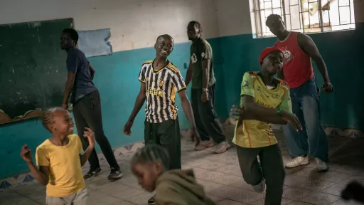 Indoor activity space with teal walls where children and youth of various ages interact