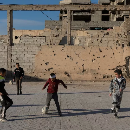 four young boys are playing soccer in the middle of ruins 