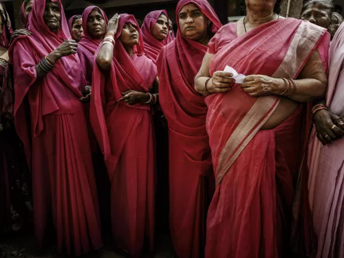 Women dressed in pink saris, photographed in a medium shot, fill the entire frame