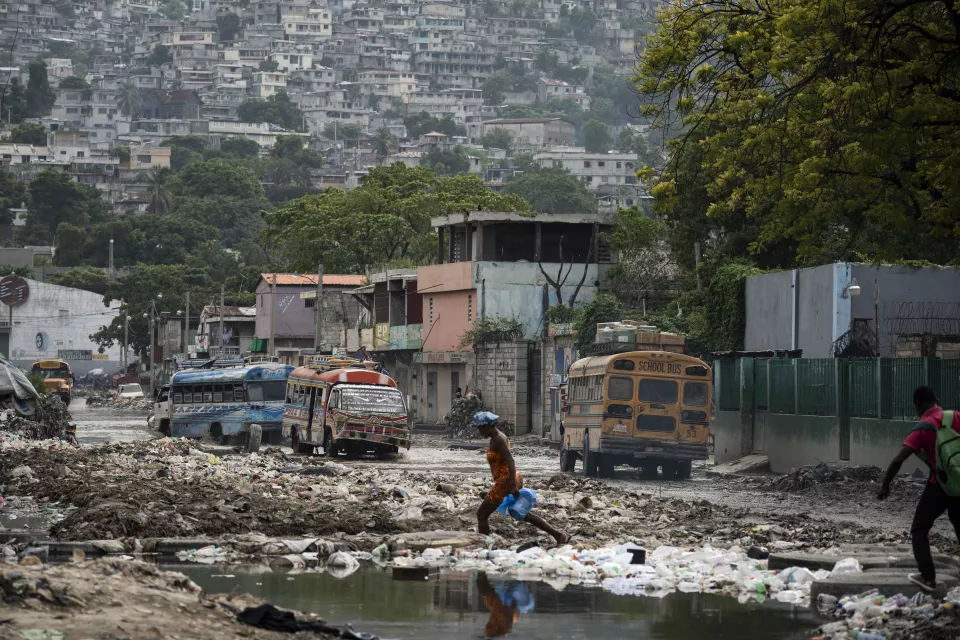 Urban street covered in mud and debris with colorful buses