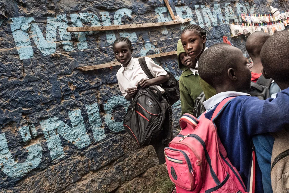 Four young students standing against a weathered wall