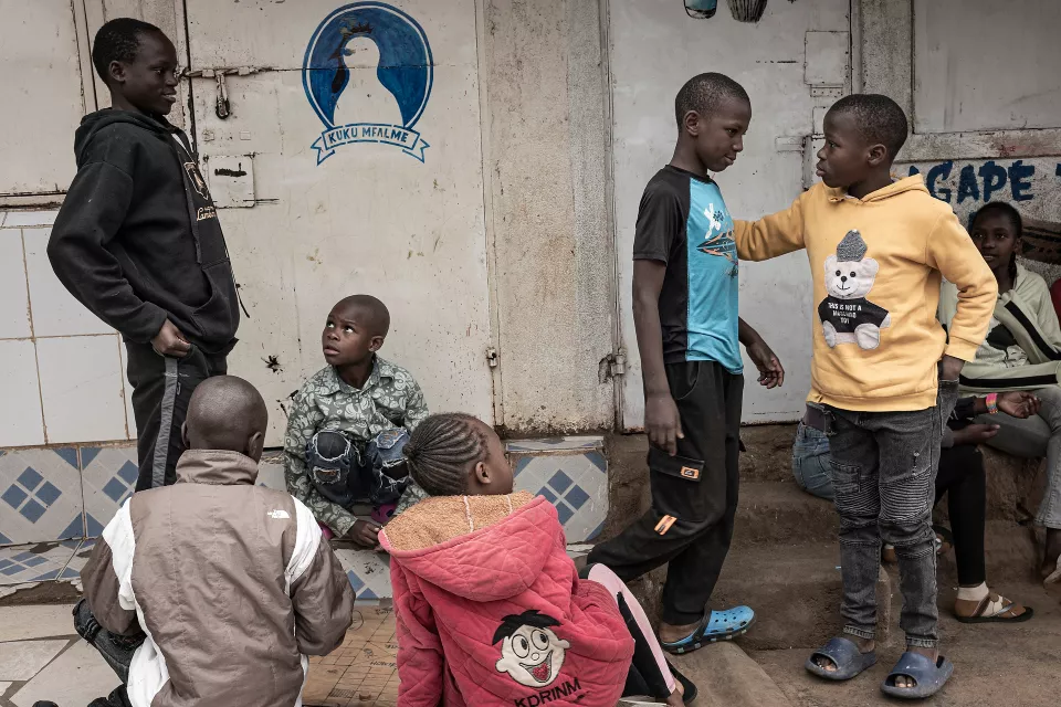 Group of children of varying ages standing against a wall