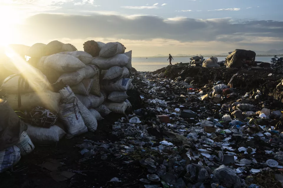 Large stack of filled sacks at sunrise or sunset beside water