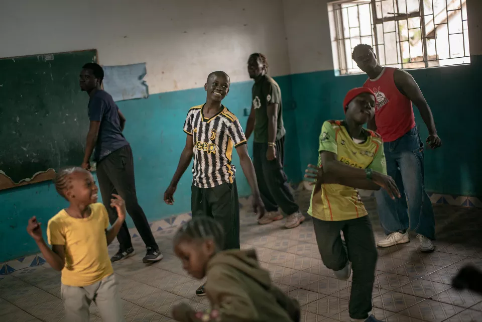 Indoor activity space with teal walls where children and youth of various ages interact