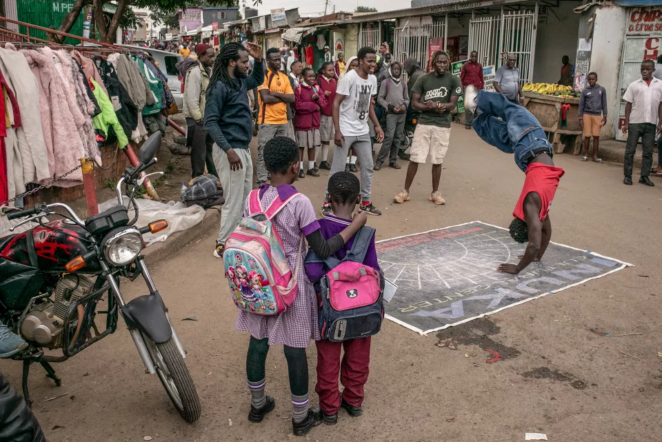Street gathering with youth performing acrobatic backflips