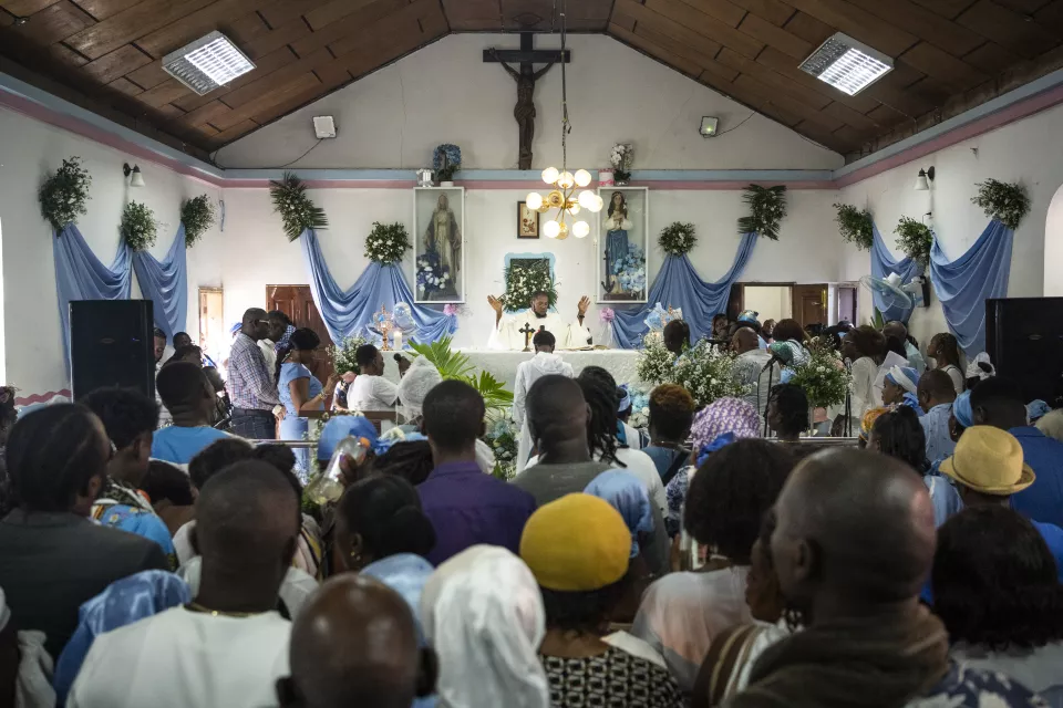 Interior of church during service, congregation facing altar with priest