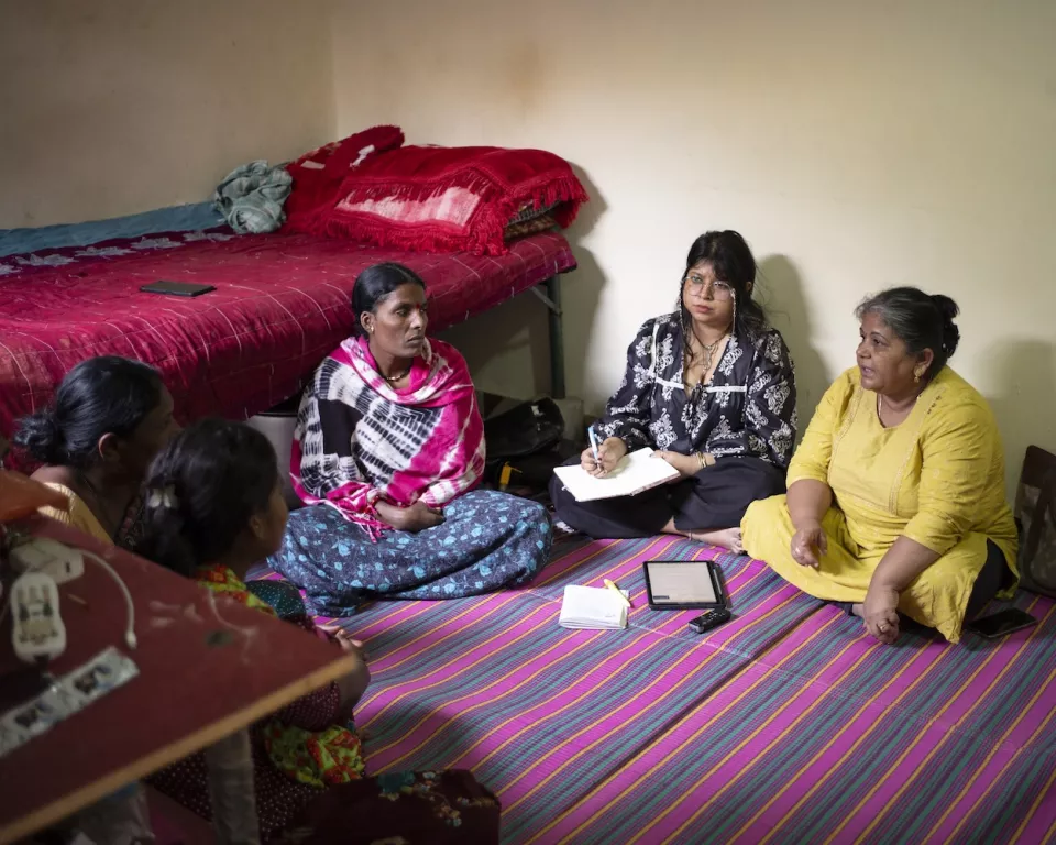 Meeting of women sitting in circle on striped mat in bedroom