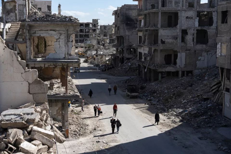 aerial view of a destroyed city street with residents without any vehicles