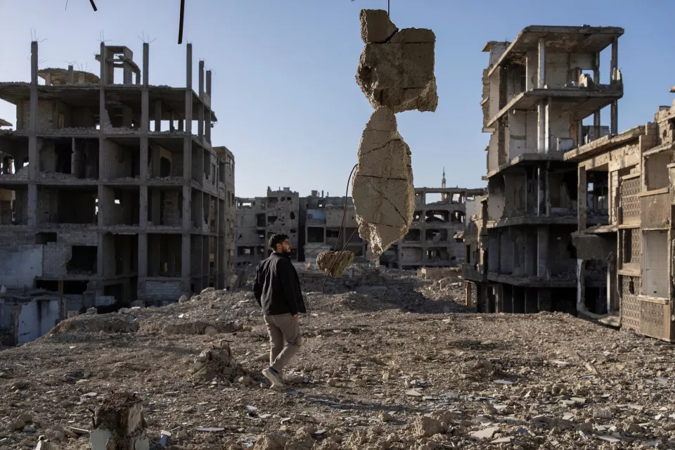 A man, Dr. Khaldoun Muawiyah Al-Mallah, walks through the ruins of the city.