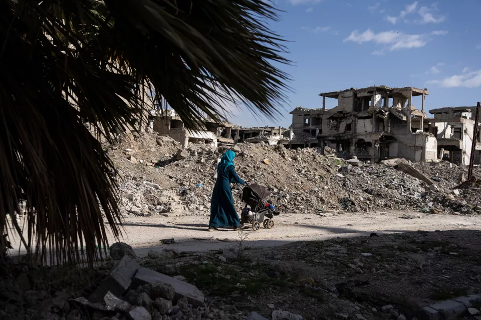 a woman pushes a stroller through the ruins 