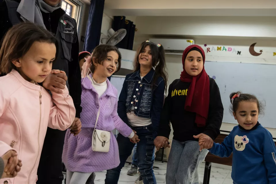 Five young, well-dressed girls and their chaperone are waiting in a classroom for a movie to start.