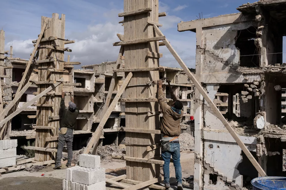 Volunteers rebuild a house amid the ruins.