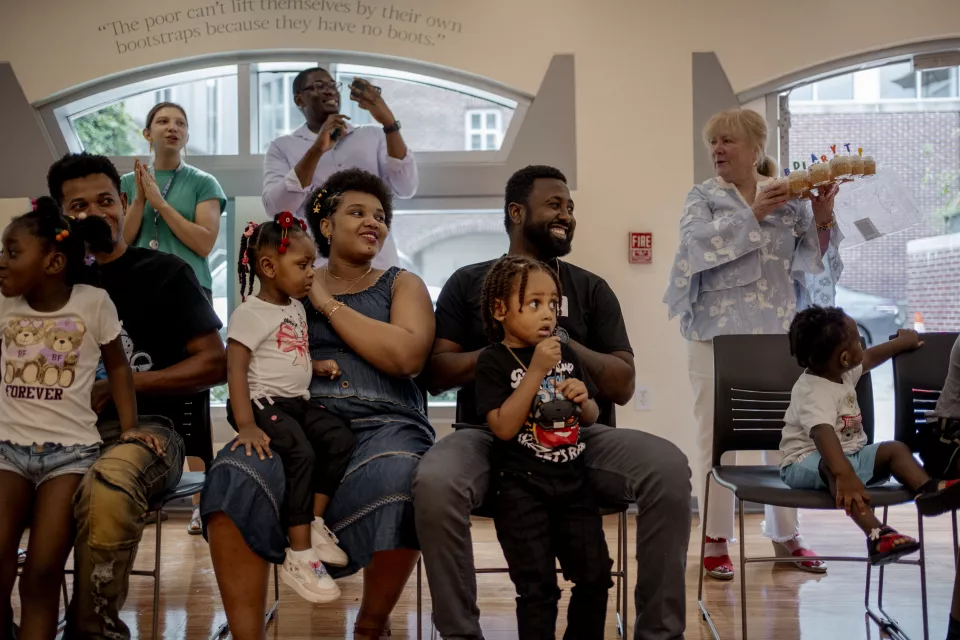 Parents of all colors, sitting in front of Mary McCabe who holds the birthday cakes during the Back to School HT event, Georgetown